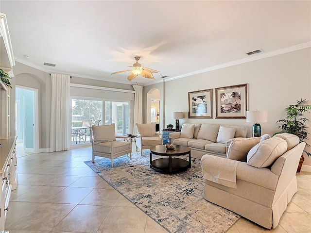 living room with light tile patterned floors, visible vents, arched walkways, ceiling fan, and ornamental molding