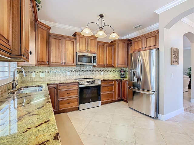 kitchen featuring a sink, stainless steel appliances, arched walkways, and brown cabinetry