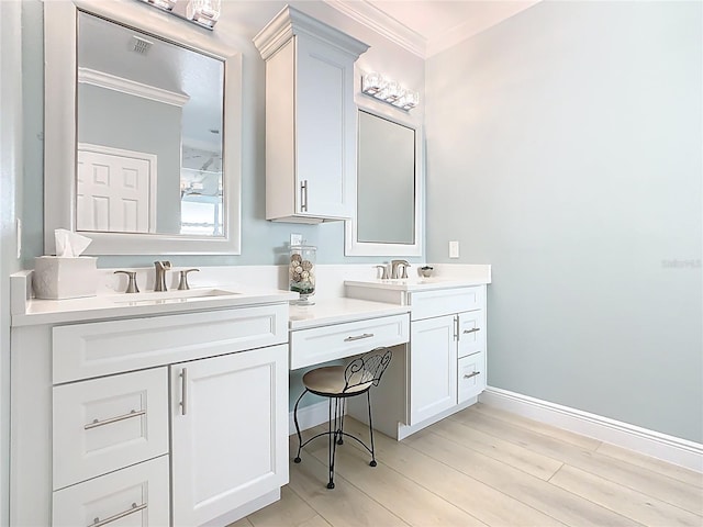 bathroom featuring a sink, wood finished floors, crown molding, double vanity, and baseboards