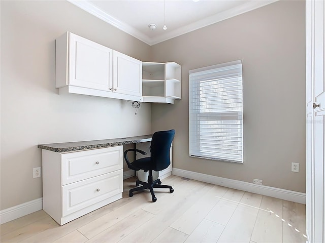 home office with light wood-style flooring, baseboards, ornamental molding, and built in desk