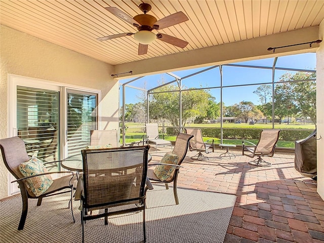 view of patio / terrace featuring a lanai, ceiling fan, and outdoor dining space