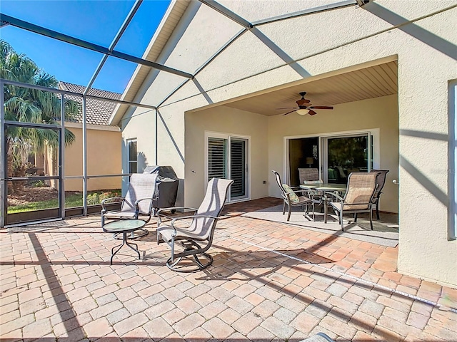 view of patio / terrace featuring glass enclosure and a ceiling fan