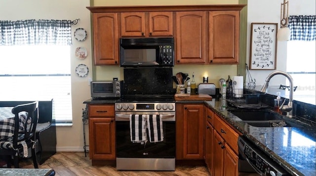 kitchen with dark stone countertops, a toaster, a sink, black appliances, and brown cabinets