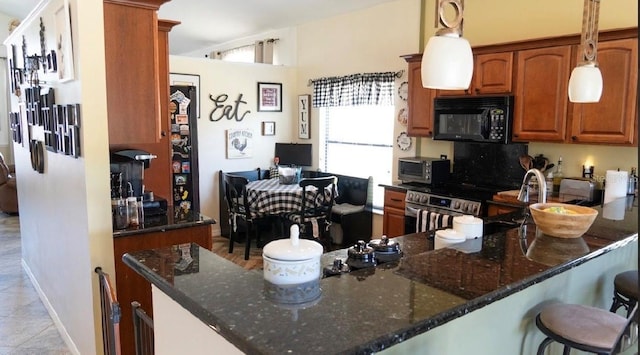 kitchen featuring dark stone countertops, a breakfast bar, brown cabinetry, and black microwave