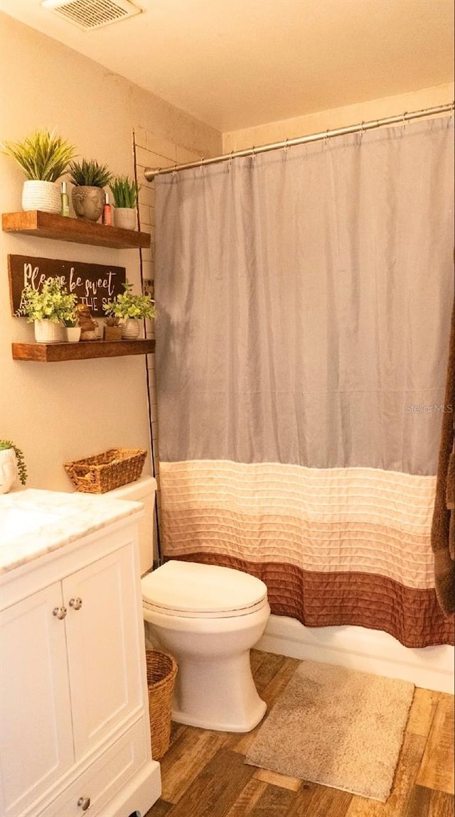 bathroom featuring vanity, a shower with shower curtain, wood finished floors, visible vents, and toilet