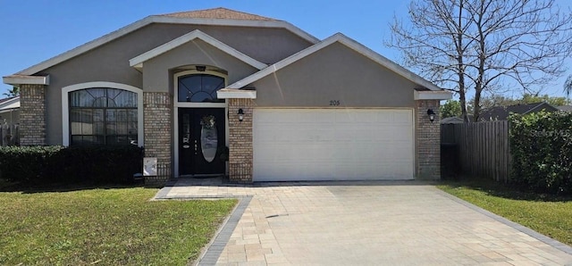 ranch-style house featuring decorative driveway, an attached garage, brick siding, and stucco siding