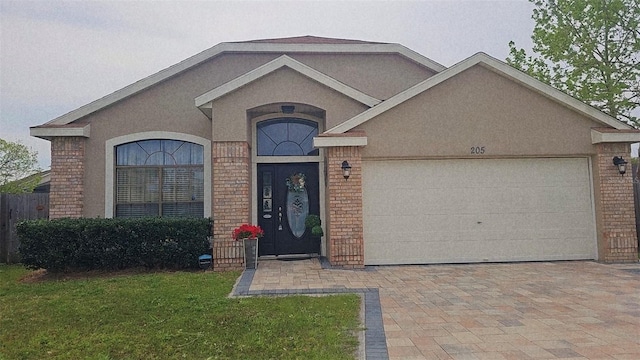 view of front of home featuring an attached garage, stucco siding, and brick siding