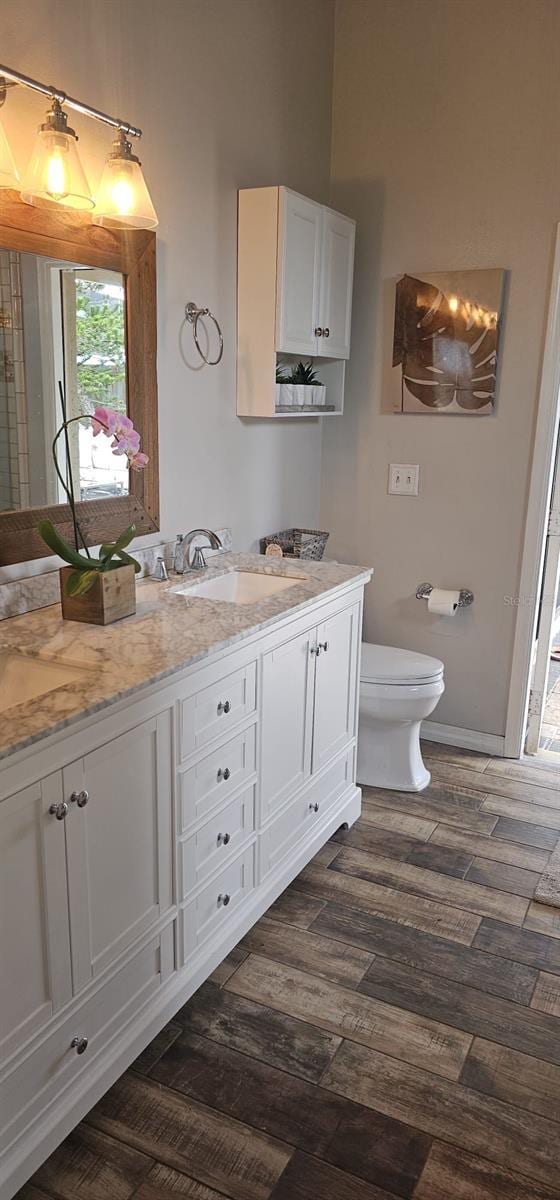 bathroom featuring toilet, wood finished floors, vanity, and baseboards