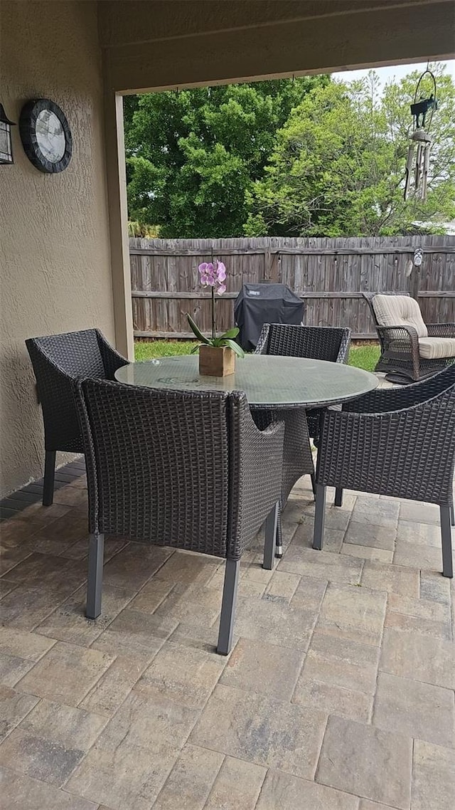 view of patio with outdoor dining space, grilling area, and fence
