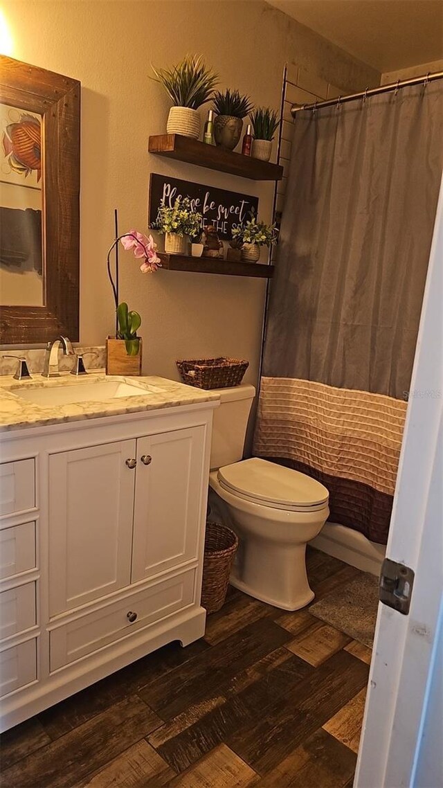 full bath with toilet, a shower with shower curtain, vanity, and wood finished floors