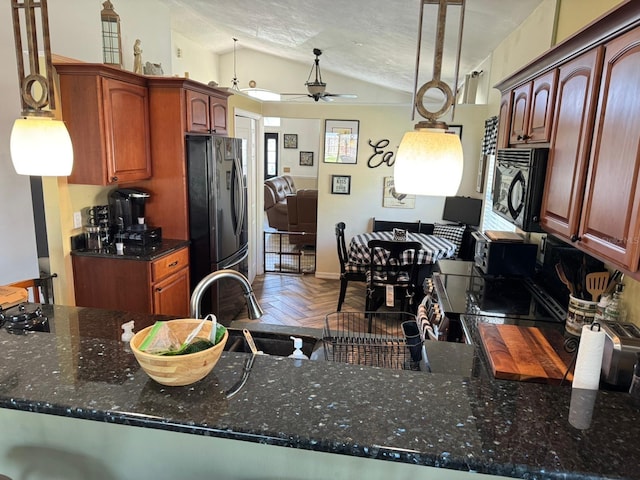 kitchen featuring a ceiling fan, black appliances, dark stone countertops, lofted ceiling, and hanging light fixtures