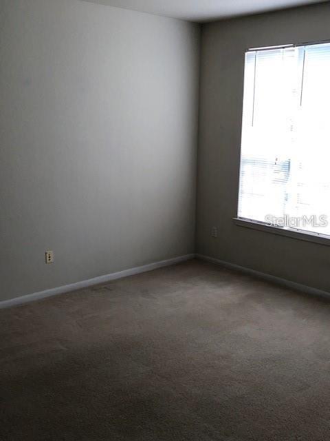 9061 Lee Vista Blvd Unit 1303, Orlando, FL 32829 - empty room featuring dark carpet and baseboards