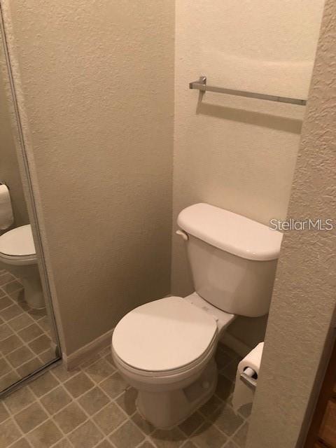 9061 Lee Vista Blvd Unit 1303, Orlando, FL 32829 - bathroom featuring toilet, a textured wall, and tile patterned flooring