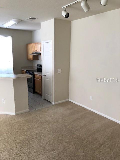 9061 Lee Vista Blvd Unit 1303, Orlando, FL 32829 - kitchen featuring stainless steel electric stove, light carpet, under cabinet range hood, baseboards, and rail lighting