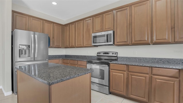 kitchen with a center island, dark stone counters, light tile patterned floors, and stainless steel appliances