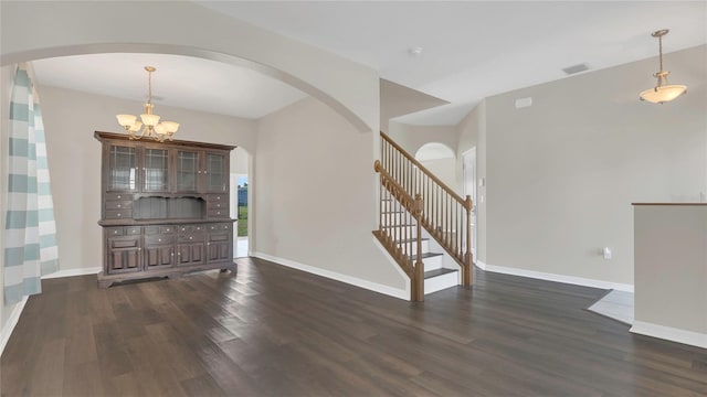 unfurnished living room featuring baseboards, stairs, dark wood-style floors, an inviting chandelier, and arched walkways