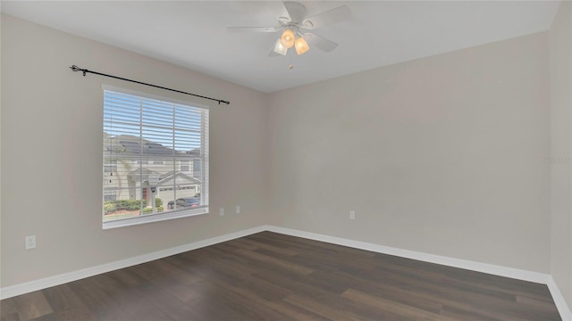 spare room featuring dark wood finished floors, a ceiling fan, and baseboards