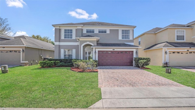 traditional-style house featuring a front lawn, a garage, driveway, and stucco siding