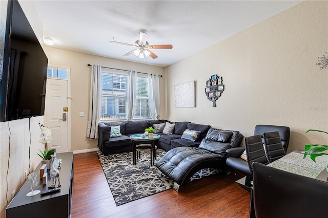 living room with baseboards, wood finished floors, ceiling fan, and a textured wall