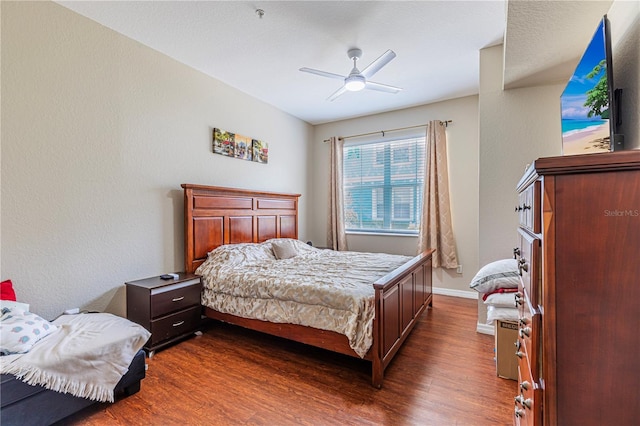 bedroom with baseboards, dark wood-type flooring, and ceiling fan