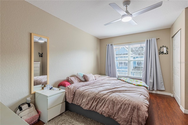 bedroom with ceiling fan, baseboards, wood finished floors, and a textured wall