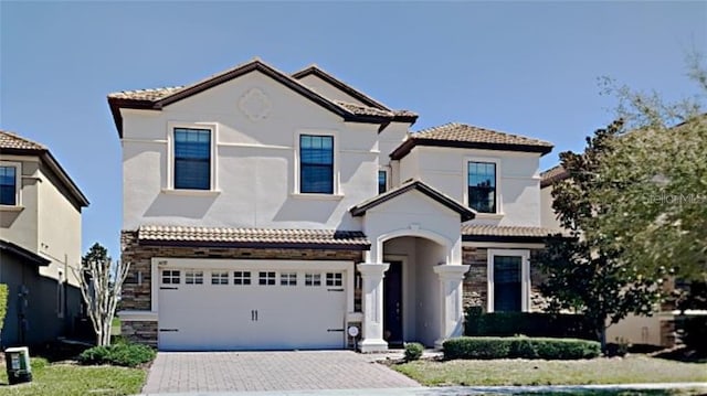1432 Rolling Fairway Dr, Davenport, FL 33896 - mediterranean / spanish home featuring stucco siding, driveway, stone siding, a garage, and a tiled roof