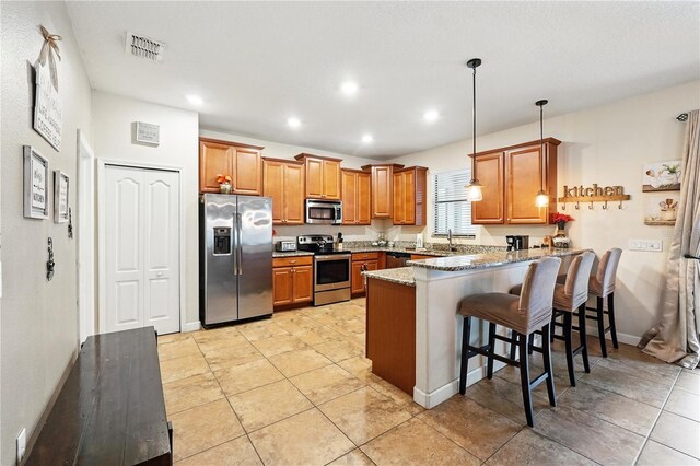1432 Rolling Fairway Dr, Davenport, FL 33896 - kitchen featuring visible vents, a peninsula, brown cabinetry, stainless steel appliances, and light stone counters
