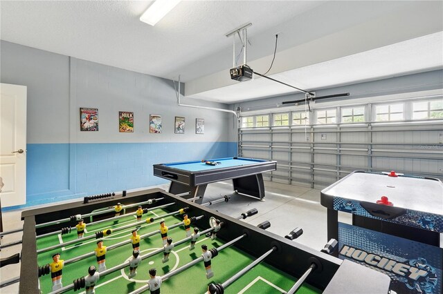 1432 Rolling Fairway Dr, Davenport, FL 33896 - recreation room with concrete block wall, a textured ceiling, a garage, and a healthy amount of sunlight