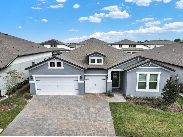view of front of home with stucco siding, decorative driveway, an attached garage, and a shingled roof