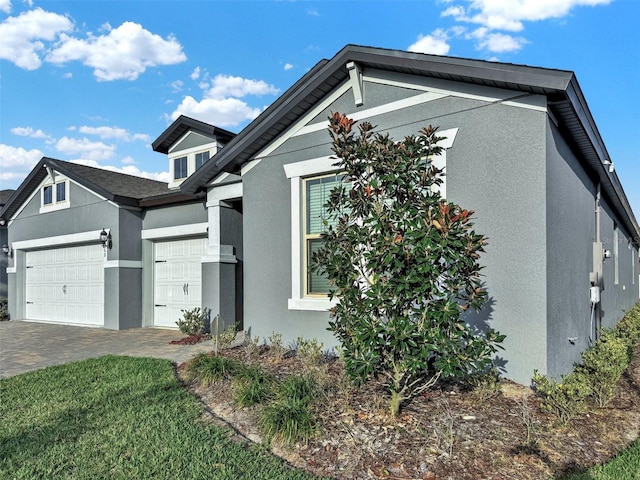 view of home's exterior with stucco siding, driveway, and an attached garage