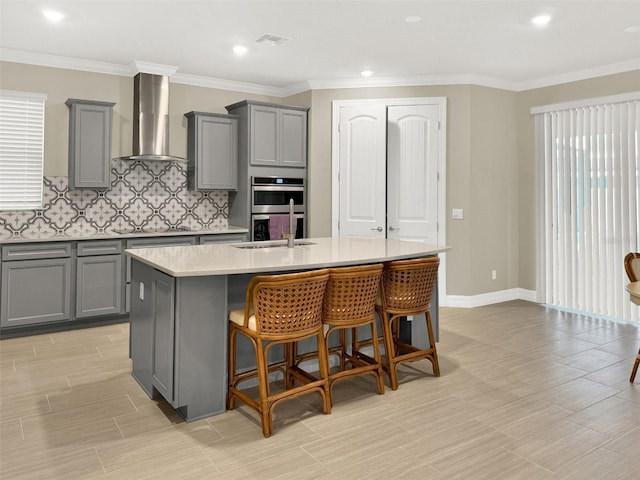 kitchen featuring stainless steel double oven, gray cabinetry, and wall chimney range hood