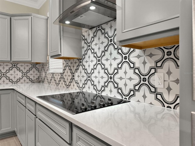kitchen with ornamental molding, gray cabinets, backsplash, ventilation hood, and black electric stovetop