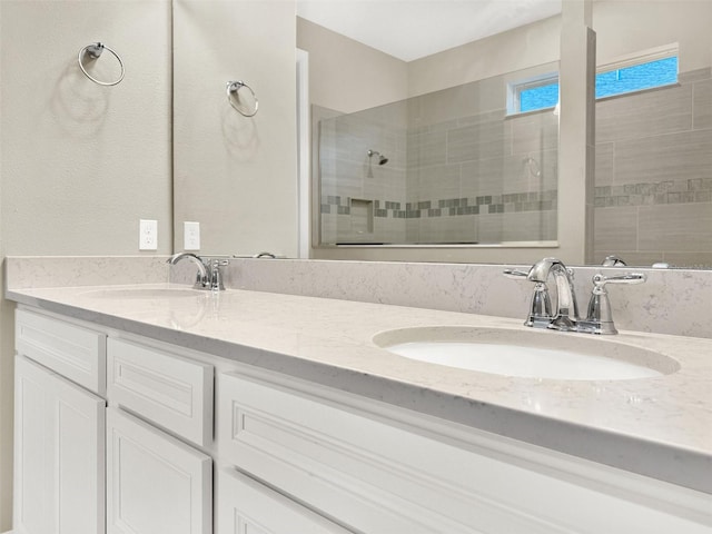 full bath with a tile shower, double vanity, and a sink