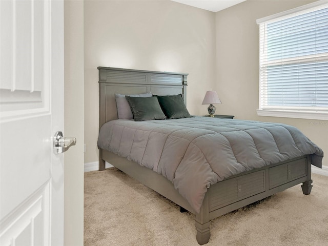 bedroom with light colored carpet and baseboards