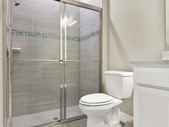 bathroom featuring vanity, toilet, and a stall shower
