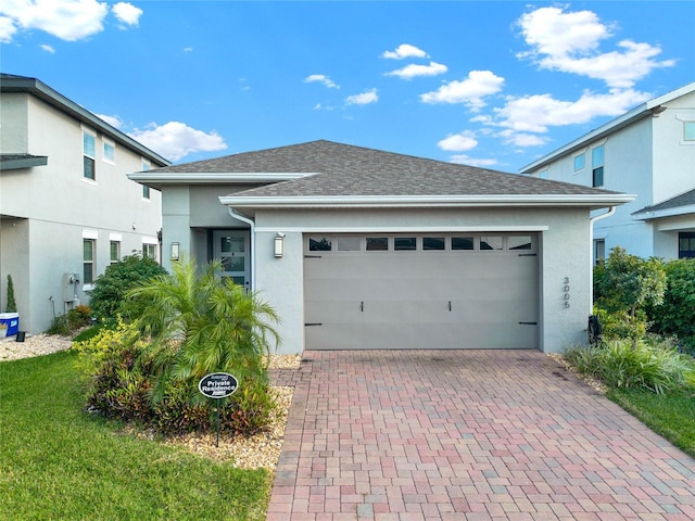 view of front of property featuring decorative driveway, a shingled roof, an attached garage, and stucco siding
