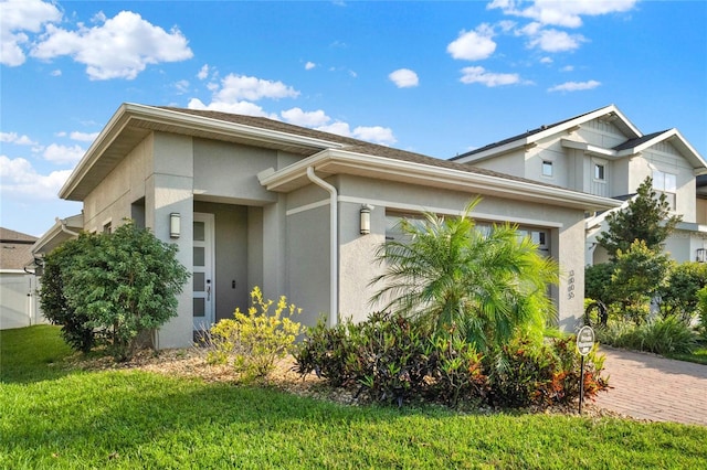 view of front of home with a garage, stucco siding, decorative driveway, and a front lawn