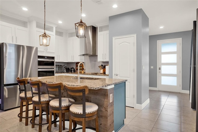 kitchen featuring a breakfast bar, light stone counters, tasteful backsplash, stainless steel appliances, and wall chimney exhaust hood