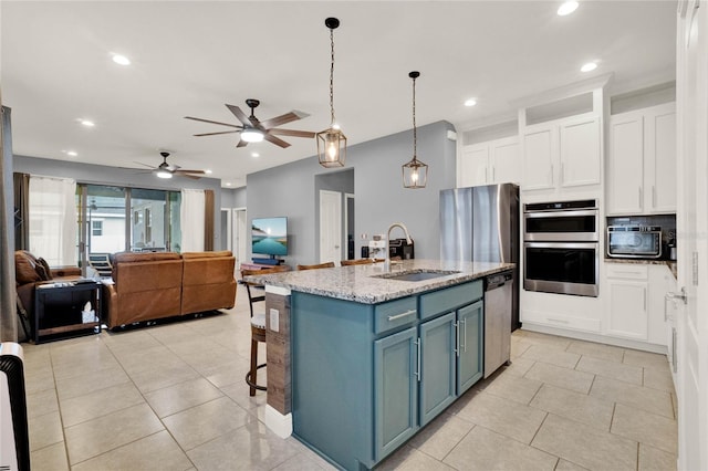kitchen featuring open floor plan, stainless steel appliances, white cabinetry, a ceiling fan, and a sink