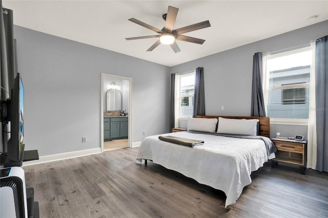 bedroom featuring multiple windows, baseboards, and wood finished floors