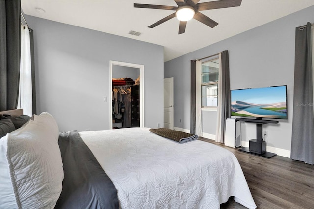 bedroom featuring wood finished floors, visible vents, baseboards, ceiling fan, and a spacious closet