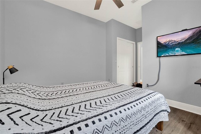 bedroom featuring ceiling fan, visible vents, baseboards, and wood finished floors