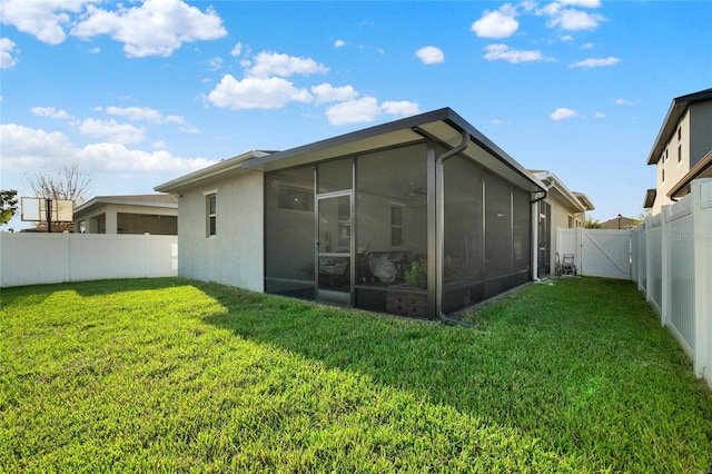 rear view of house featuring a yard, a fenced backyard, stucco siding, and a sunroom