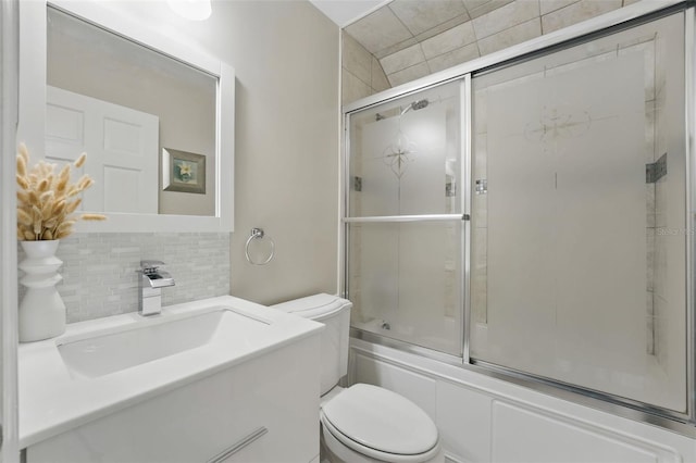 bathroom featuring backsplash, toilet, enclosed tub / shower combo, and vanity
