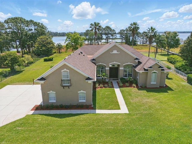 view of front of house featuring a water view, fence, a front yard, and stucco siding