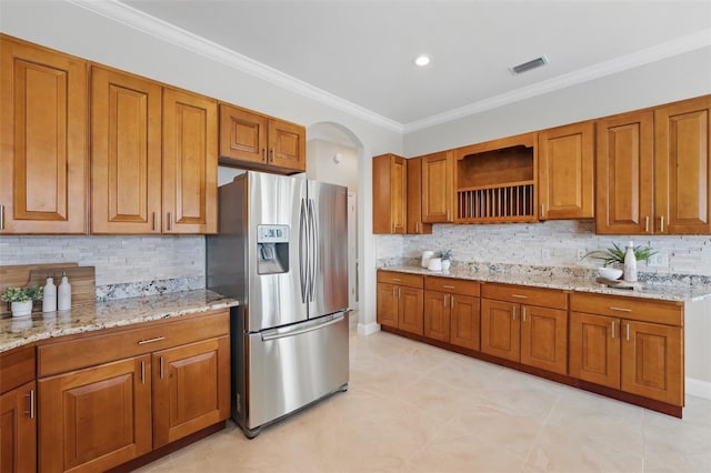 kitchen featuring brown cabinets, light stone countertops, stainless steel fridge with ice dispenser, tasteful backsplash, and visible vents