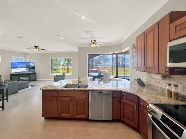 kitchen featuring stainless steel appliances, a ceiling fan, a sink, a peninsula, and light stone counters