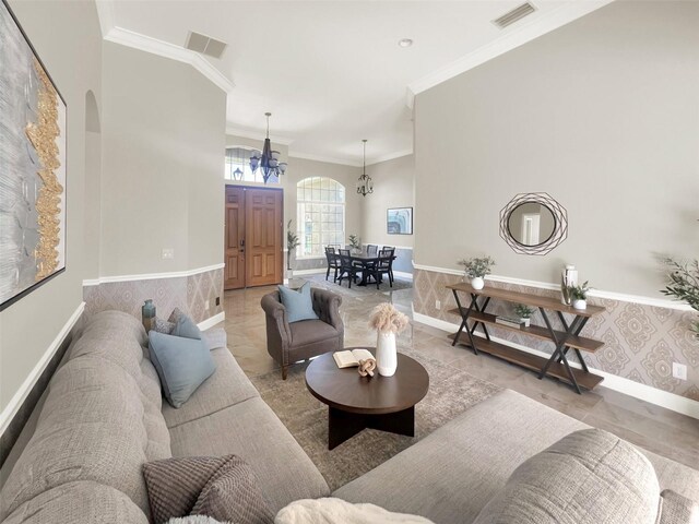 living area with arched walkways, a chandelier, ornamental molding, baseboards, and light tile patterned floors