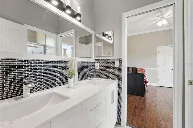 bathroom with crown molding, ceiling fan, backsplash, hardwood / wood-style floors, and double vanity