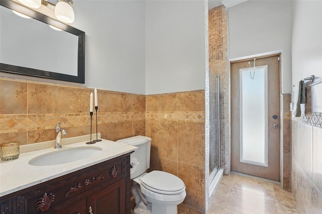 bathroom featuring tile walls, toilet, a stall shower, vanity, and wainscoting